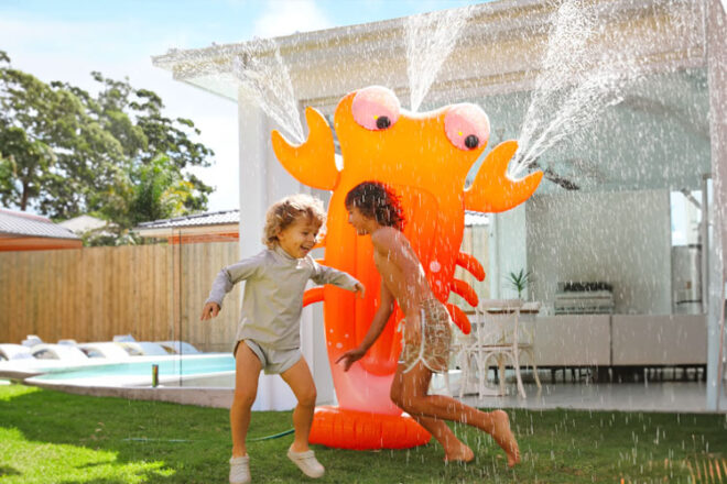 two children playing with the SUNNYLiFE Inflatable Giant Sprinkler Sonny the Sea Creature