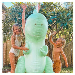 two children playing with the SUNNYLiFE Inflatable Giant Sprinkler Surfing Dino