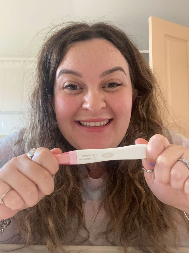 Rose holding up positive pregnancy test