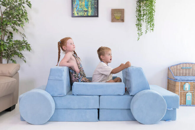 two children sitting on a play couch shaped like a car