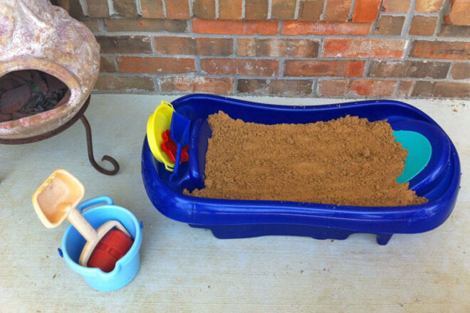 An old baby bath repurposed as a sand pit