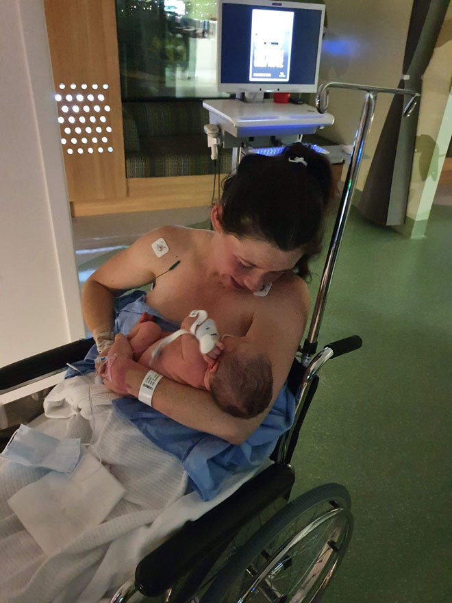 Jacki in a wheelchair holding her newborn