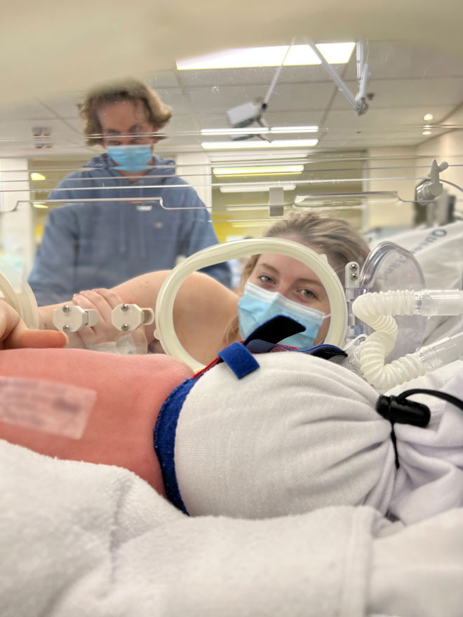 A mum looks at her baby in the NICU crib