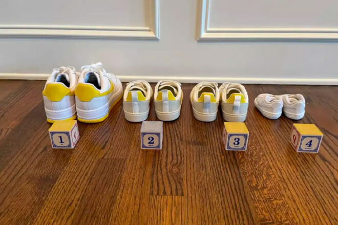 Four pair of white and yellow sneakers lined up with numbered wooden blocks counting from one to four in front of each pair