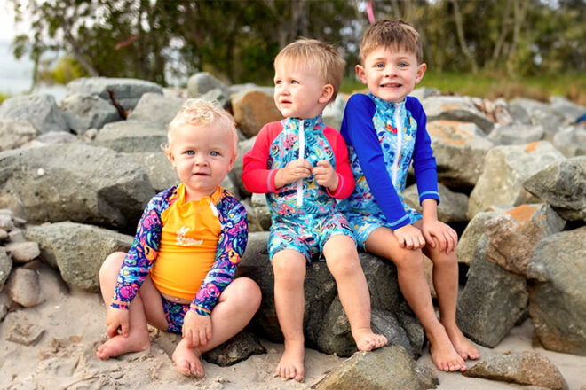 three boys sitting on the rocks in TicTasTogs swimsuits
