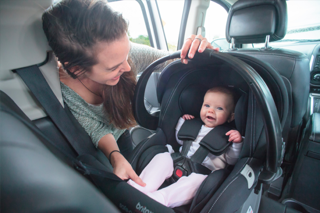 Mum sitting in backseat of car talking to baby in a car seat capsule