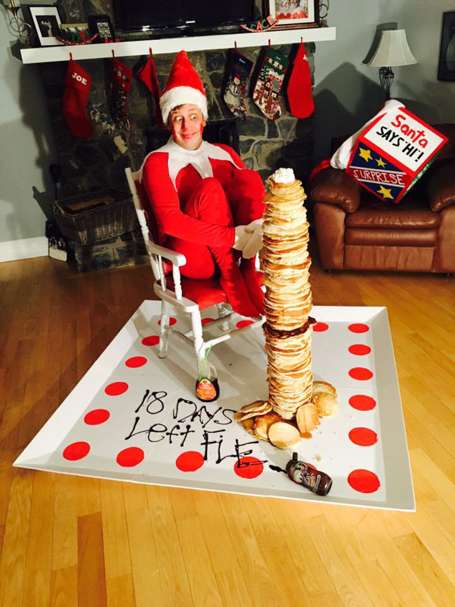 Dad dresses as elf on the shelf sitting on a plate with a giant stack of pancakes
