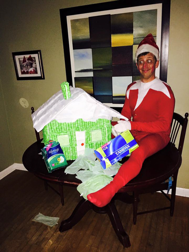 Dad dresses as elf on the shelf making a gingerbread house out of Tampax 