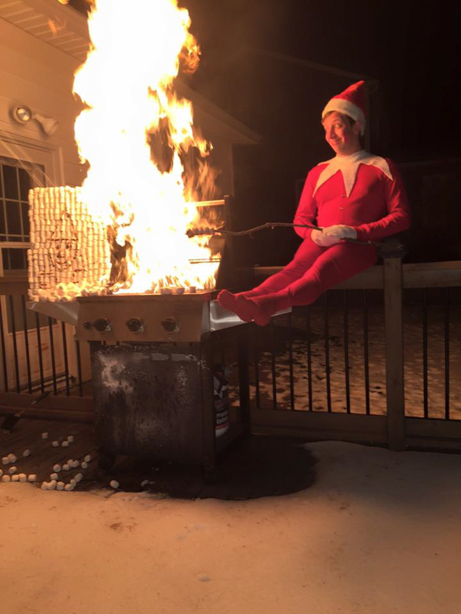 Dad dresses as elf on the shelf making a huge fire whilst sitting on the nearest fence