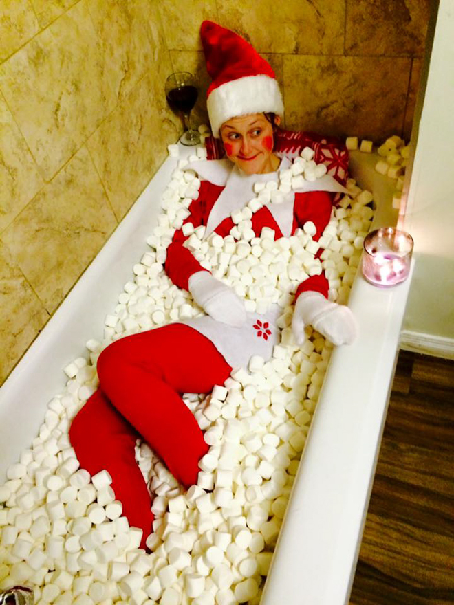 Mum dresses as elf on the shelf laying in a bathtub filled with marshmallows