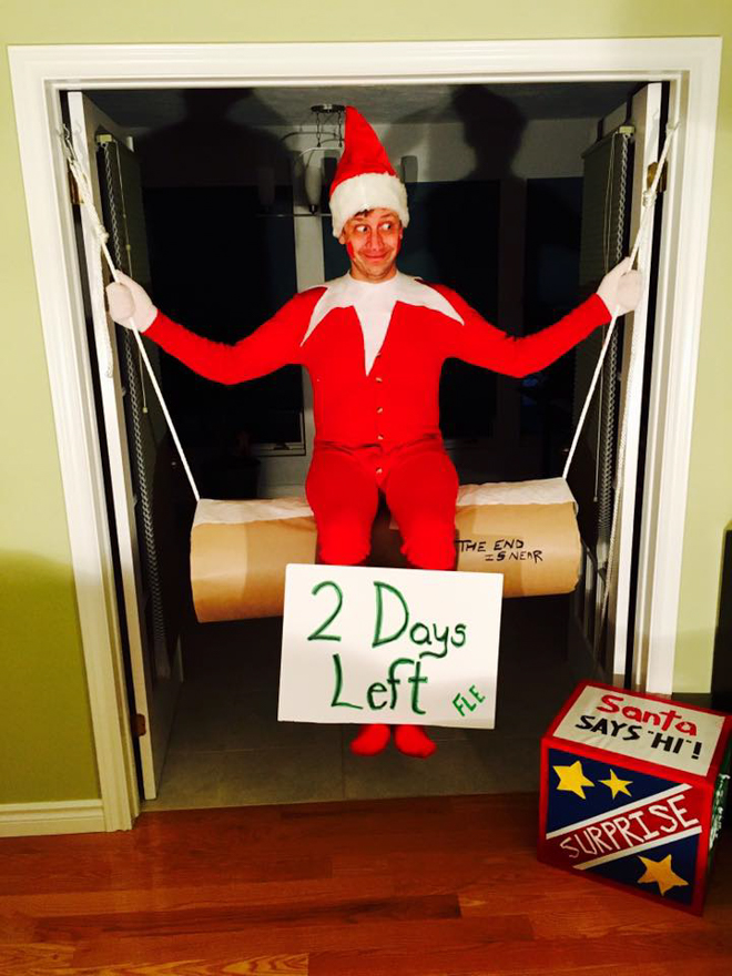 Dad dresses as elf on the shelf hanging on a roll of toilet paper