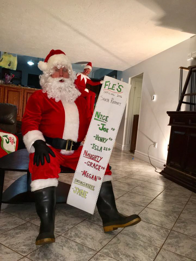 Dad dresses as elf on the shelf and appears to be sitting on Santas shoulder with a list of naughty and nice family