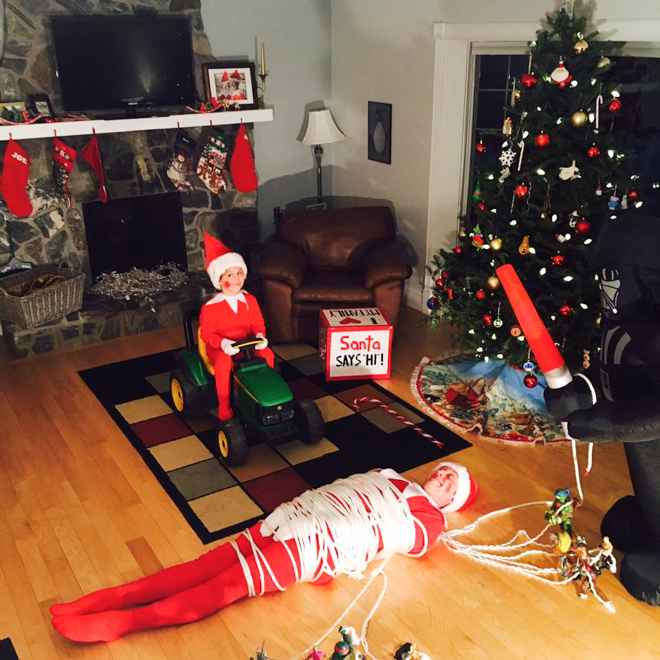 Dad dresses as elf on the shelf with child dressed as elf pretending to run over tied up dad