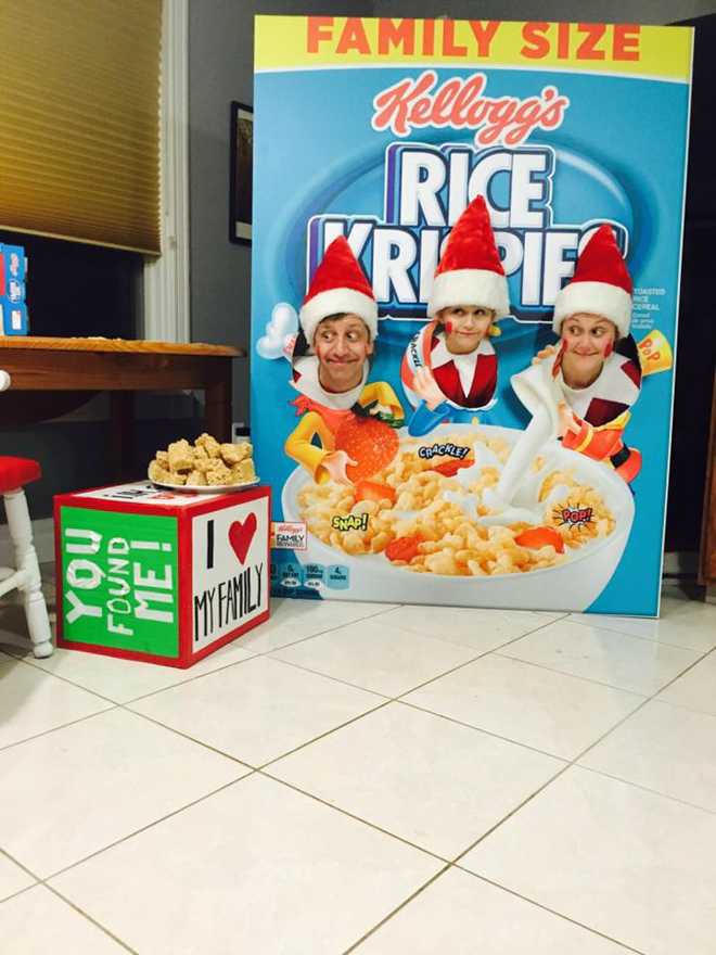Family dresses as elf on the shelf with heads popping through a large box of Rice Krispies