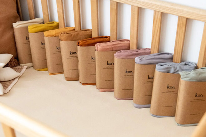 Kiin Baby Cot Sheets showing their range of newborn sheet colour ways lined up on a bed. 