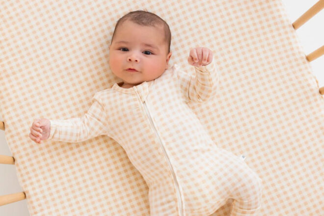 Baby lying on the KYND Baby fitted cot sheet