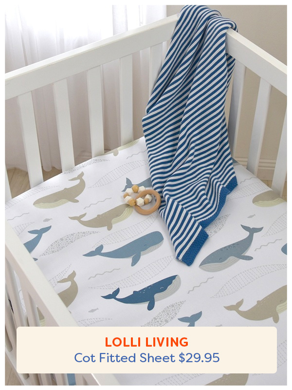 The Lolli Living fitted cot sheet in a cot with a toy and blanket