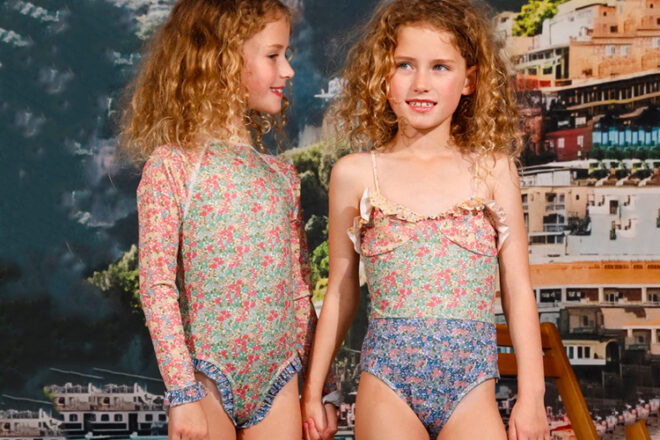 two young girls wearing Marlo kids rashie and one piece swimwear with Postiano in the background. 