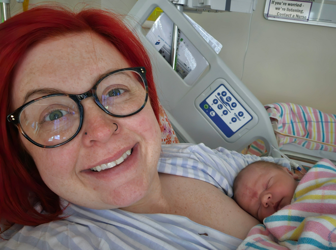 Nicole smiles holding her baby in hospital bed