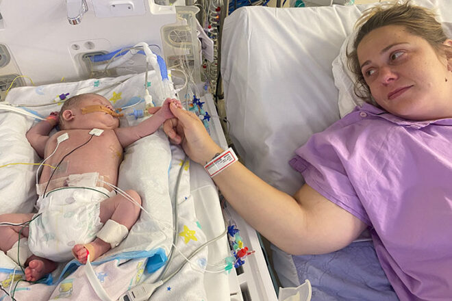 Ashleigh and her baby hold hands in hospital