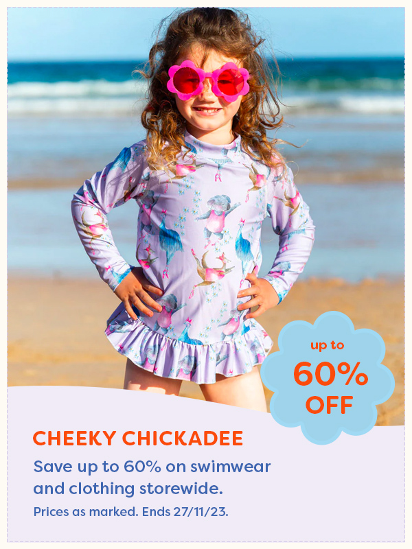 A child standing on the beach wearing Cheeky Chickadee swimwear