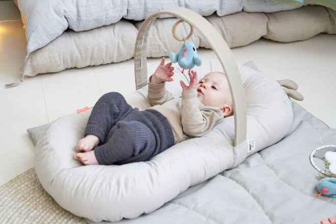 Baby lying and playing in the Done by Deer Cozy Baby Lounger