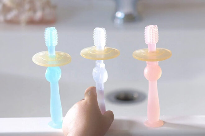 Haakaa 360 Degree Toothbrush showing a toddler reaching for a brush showing their size and assortment of colours.