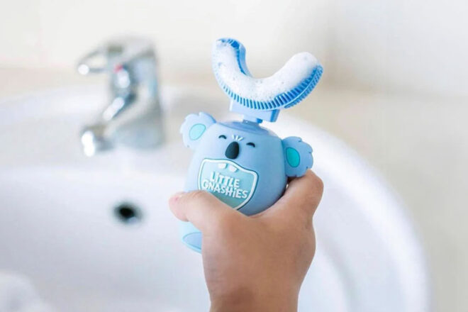 A small hand holding the Little Gnashies electric toddler toothbrush that is shaped like a Koala