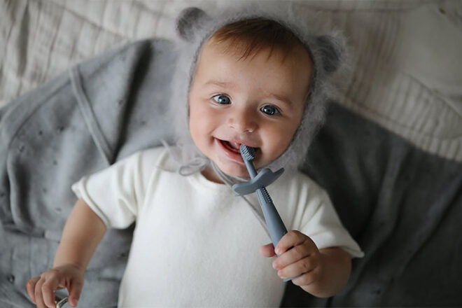 Mushie Baby showing their baby toothbrush in use with a blue colouring a star guard design
