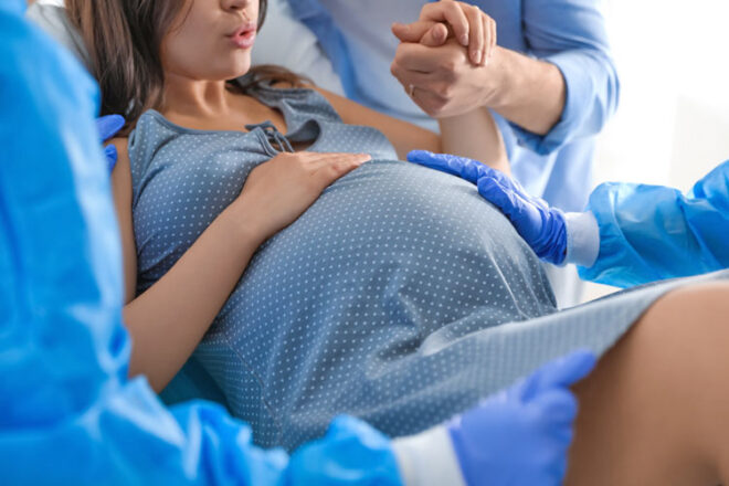 A pregnant woman in the process of giving birth surrounded by medical personal