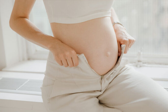A pregnant woman pulling on pants