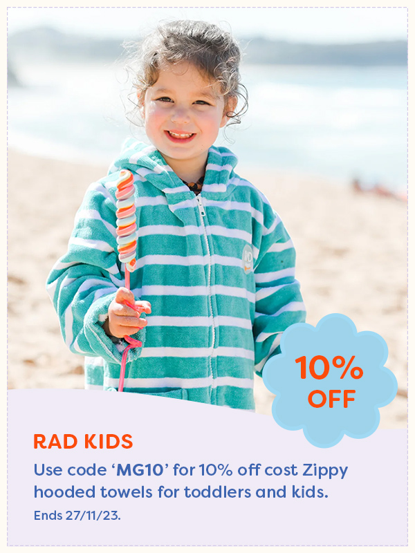 Young girl on the beach with a lollypop wearing a Rad Kids hooded towel