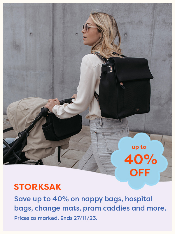 Mother pushing a stroller wearing a Storksak nappy bag