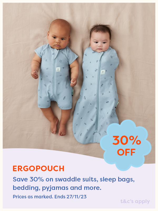 Two babies laying on a bed wearing ergoPouch sleep suits