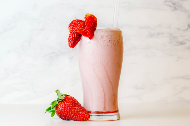 Glass of strawberry milk with fresh strawberries