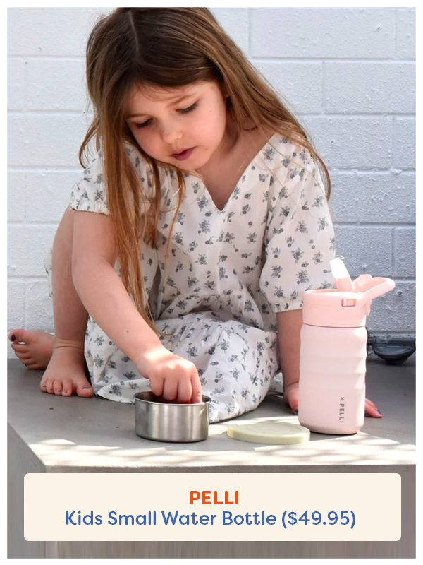 A little girl sitting holding the Pelli drink bottle in pink