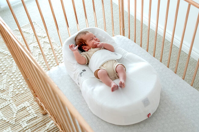 Newborn baby in a Cocoonababy baby nest in a cot