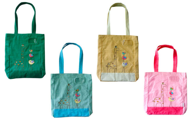 Four different coloured library bags from BamBam Kitds Toys with embroidered flowers and birds