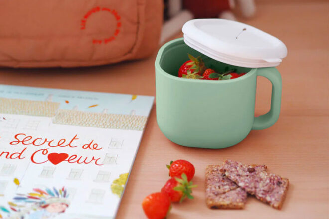 The Beaba Silicone Snack Cup in sage with strawberries inside