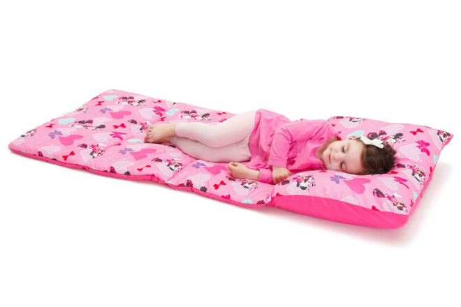 A young girl laying on a Disney Minnie Mouse Nap Mat