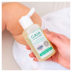A baby laying with an adult's hand showing the GAIA Baby Massage Oil