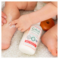A baby sitting rubbing GAIA Baby Moisturiser on their leg