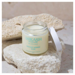 The Mikash Skincare baby barrier balm sitting on a rock with the lid taken off