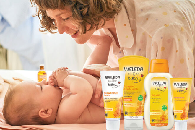 A mother leaning over her baby with the Weleda Baby Skincare products