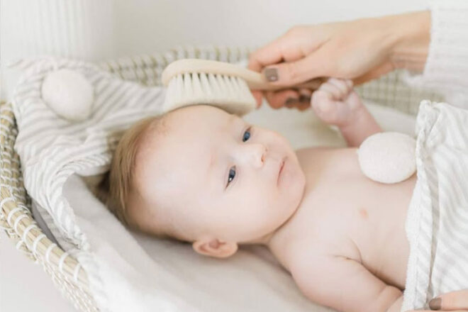 A baby having the Ali + Oli newborn hairbrush used on their head