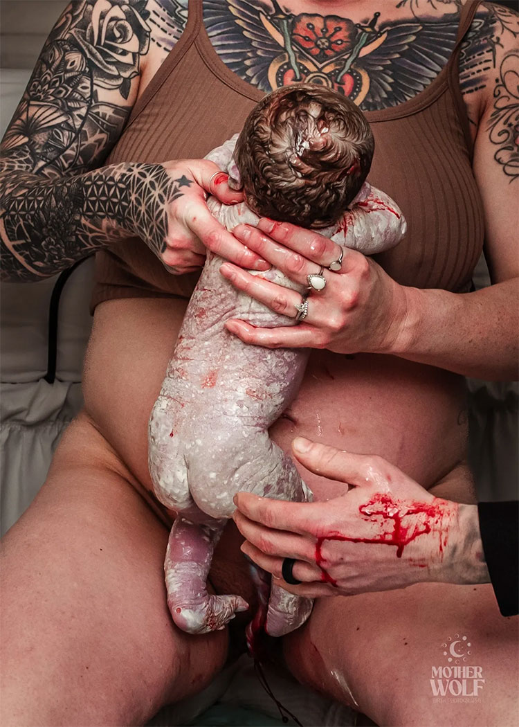 A woman helping hold her newborn baby that has just been born