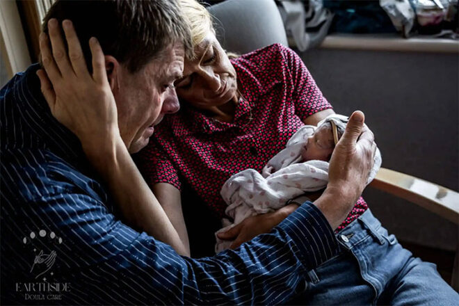Two older people holding their grandchild who was delivered stillbirth