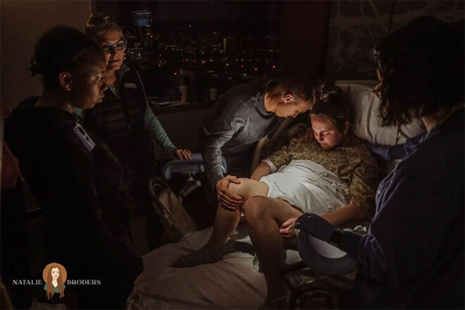 A medical team surrounding a man and a woman who is in the process of giving birth