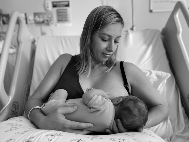 A mother breastfeeds her baby in hospital bed