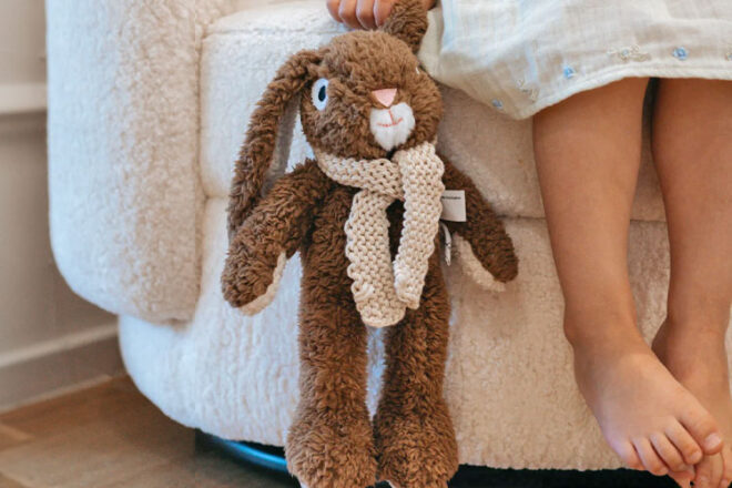 Child sitting on a couch holding Frankie the Bunny from And the little dog laughed